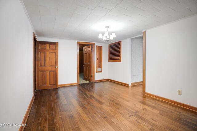 empty room with a notable chandelier and hardwood / wood-style floors