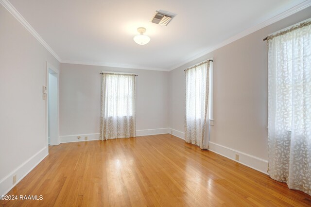 unfurnished room with light wood-type flooring and crown molding