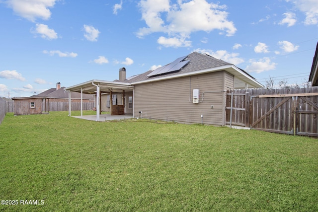 back of property featuring a yard, a patio, and solar panels