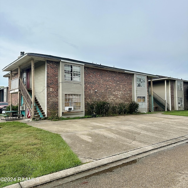 multi unit property featuring brick siding, stairway, and a front lawn