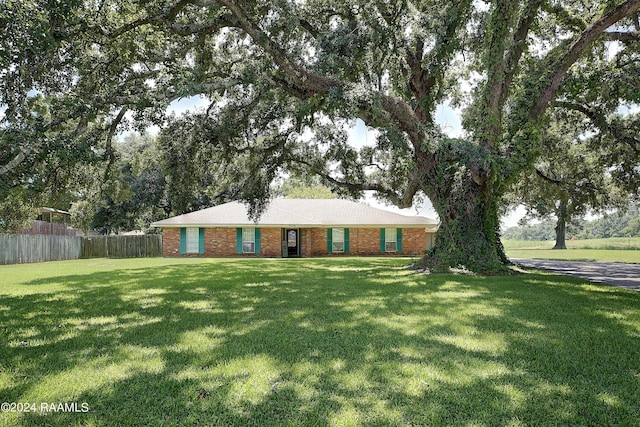 ranch-style house featuring a front lawn, fence, and brick siding