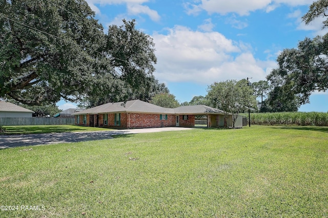 view of front of home featuring fence, driveway, a front lawn, brick siding, and an attached carport