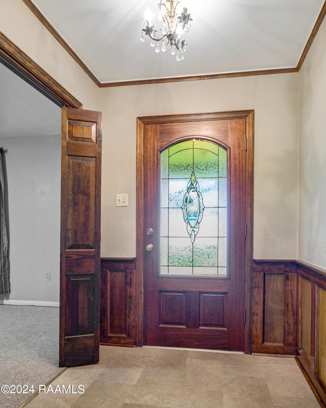 foyer entrance featuring light colored carpet, ornamental molding, wooden walls, and a chandelier