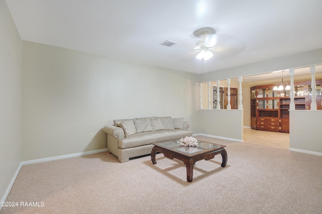 living room featuring ceiling fan with notable chandelier, baseboards, light colored carpet, and visible vents