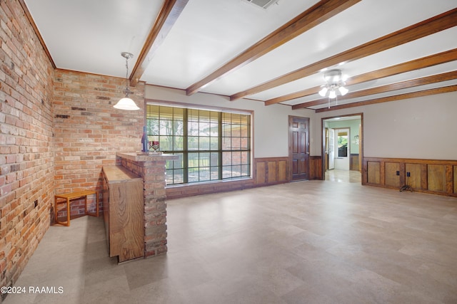 unfurnished living room with beamed ceiling, brick wall, and ceiling fan