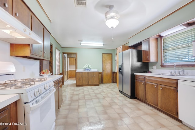 kitchen featuring white appliances, under cabinet range hood, a sink, visible vents, and brown cabinetry