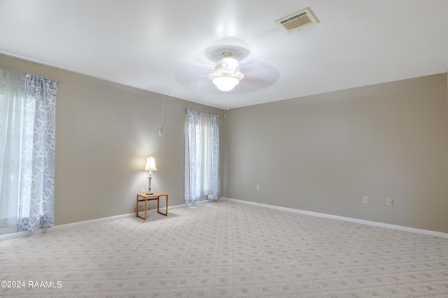 carpeted spare room with baseboards, ceiling fan, and visible vents