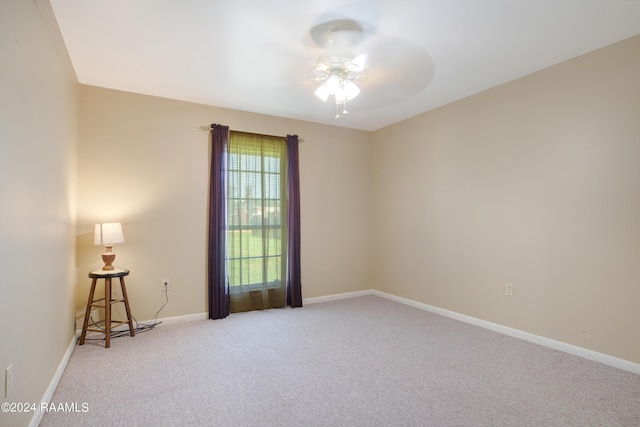 carpeted empty room featuring a ceiling fan and baseboards