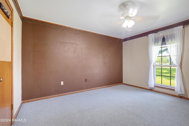 carpeted spare room with baseboards and a ceiling fan