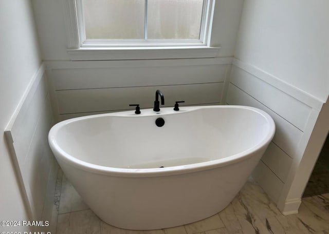 bathroom with a wainscoted wall, a freestanding tub, and marble finish floor