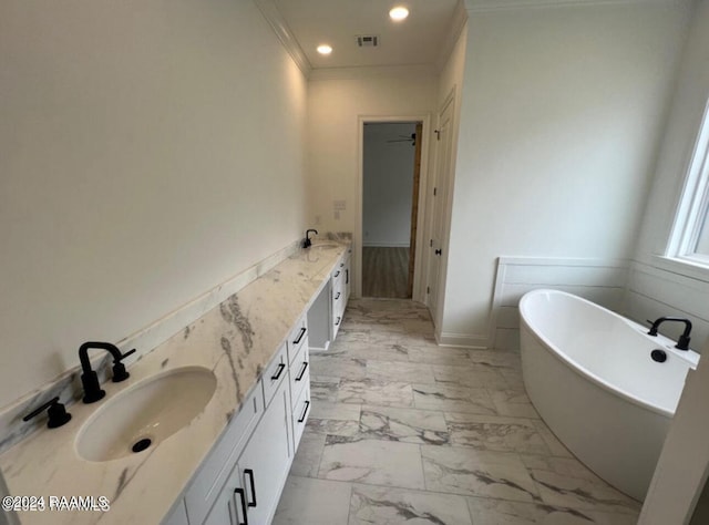 bathroom featuring a washtub, ornamental molding, and vanity