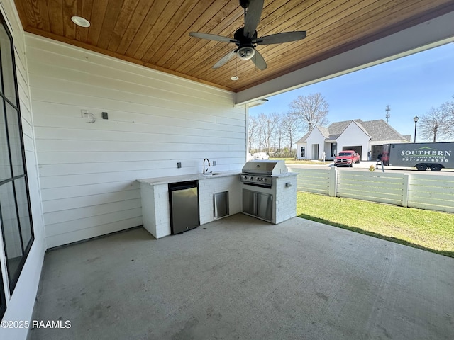 view of patio / terrace featuring ceiling fan, fence, area for grilling, an outdoor kitchen, and a sink