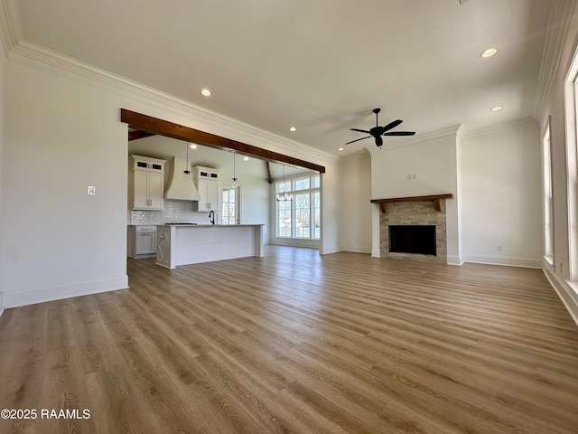 unfurnished living room with light wood-type flooring, baseboards, a fireplace, and a ceiling fan