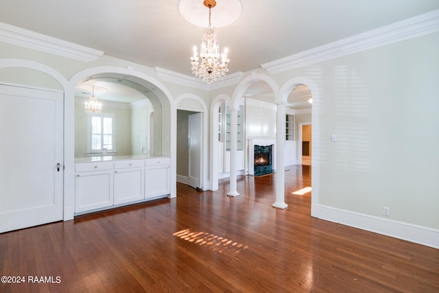 unfurnished dining area featuring crown molding, an inviting chandelier, dark wood-type flooring, and a premium fireplace