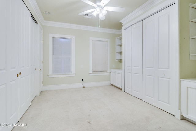 unfurnished bedroom featuring ceiling fan, light colored carpet, two closets, and crown molding