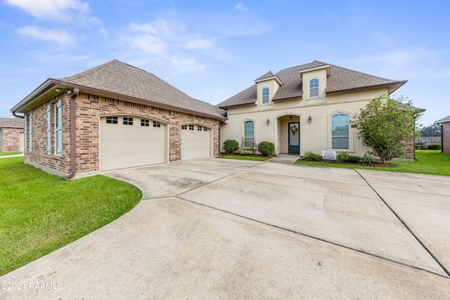 french country home featuring covered porch, a garage, and a front lawn