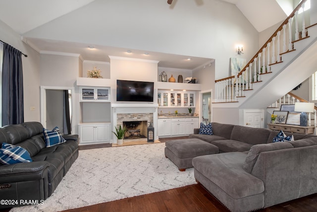 living room featuring dark wood-type flooring, ornamental molding, high vaulted ceiling, and a fireplace