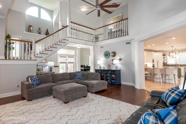 living room with a towering ceiling, ceiling fan with notable chandelier, and hardwood / wood-style flooring