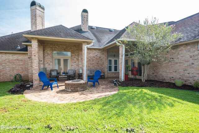 rear view of house with an outdoor fire pit, brick siding, french doors, a lawn, and a patio area