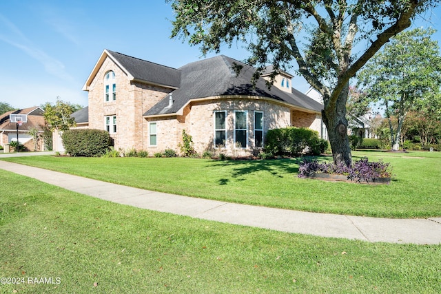 view of front of home with a front yard, brick siding, and roof with shingles