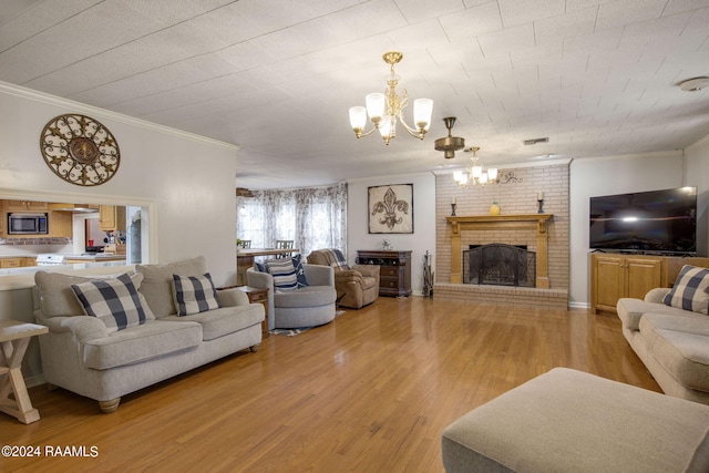 living room with ornamental molding, hardwood / wood-style floors, a fireplace, and a chandelier