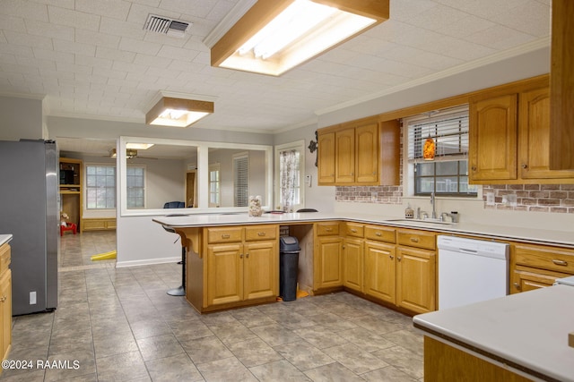 kitchen with tasteful backsplash, sink, dishwasher, kitchen peninsula, and stainless steel refrigerator