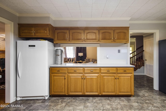 kitchen featuring crown molding, kitchen peninsula, and white refrigerator