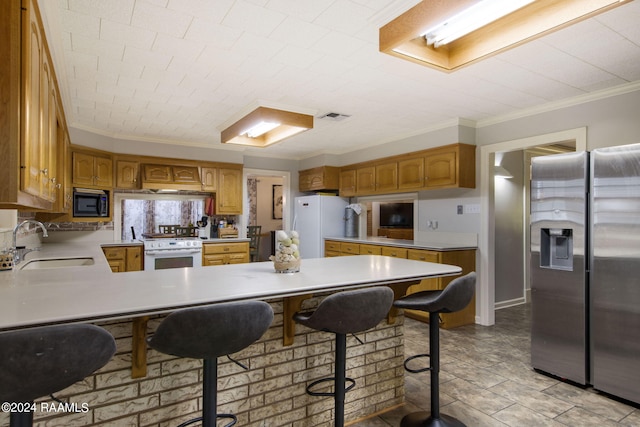 kitchen featuring kitchen peninsula, sink, crown molding, a breakfast bar, and appliances with stainless steel finishes