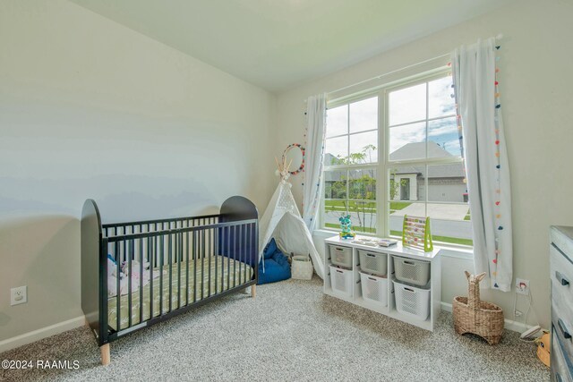 bedroom featuring light colored carpet and a nursery area