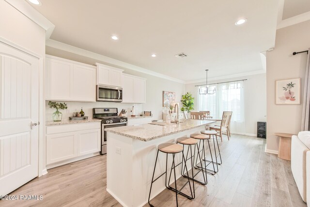 kitchen with appliances with stainless steel finishes, an island with sink, white cabinetry, and sink