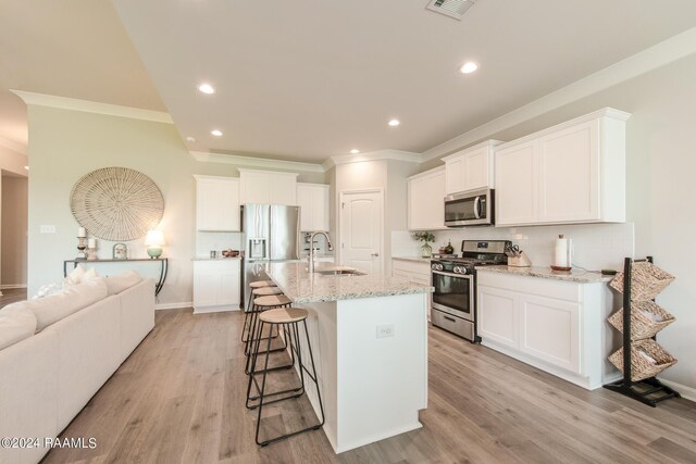 kitchen featuring a kitchen island with sink, sink, appliances with stainless steel finishes, white cabinets, and light hardwood / wood-style floors