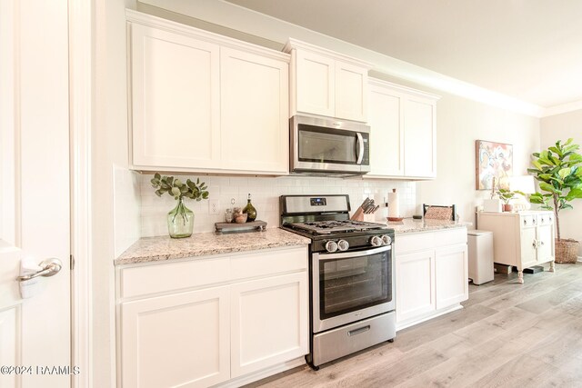 kitchen with ornamental molding, light hardwood / wood-style flooring, stainless steel appliances, and white cabinets