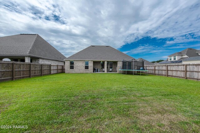 back of house with a lawn, a patio area, and a trampoline