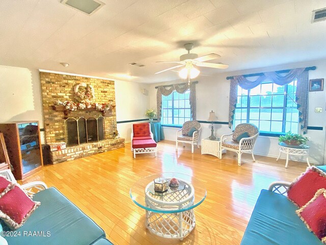 living room featuring wood-type flooring, a fireplace, ceiling fan, and a healthy amount of sunlight