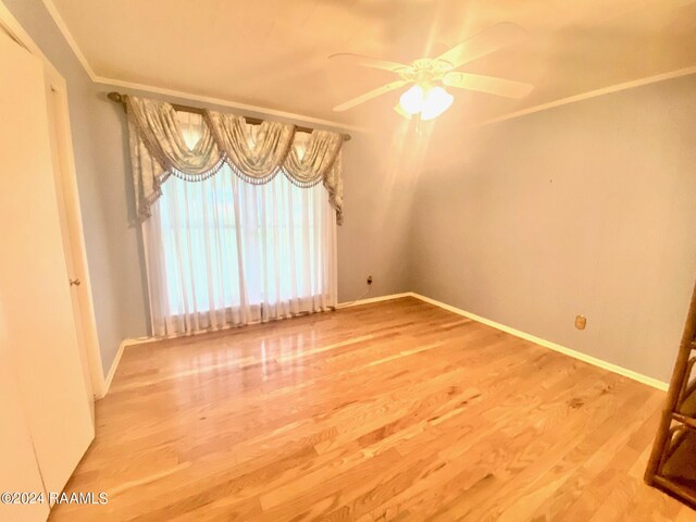 unfurnished room featuring wood-type flooring, ornamental molding, and ceiling fan