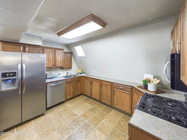 kitchen with appliances with stainless steel finishes, sink, and vaulted ceiling with skylight