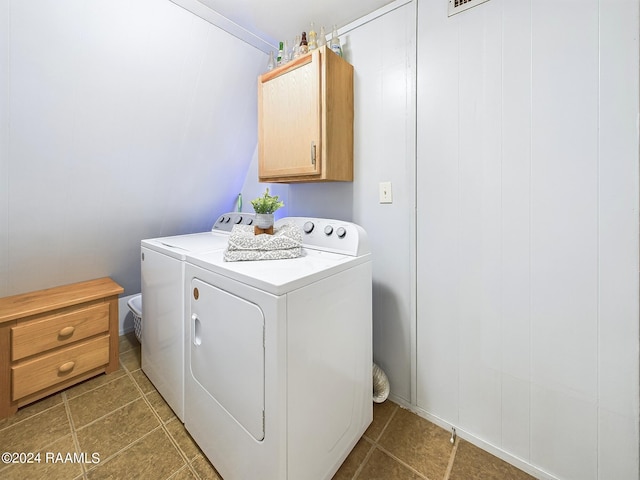 clothes washing area featuring dark tile patterned floors, cabinets, and washer and clothes dryer