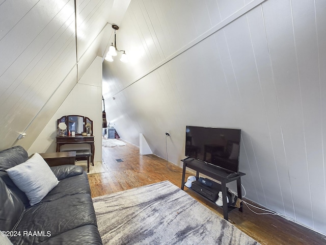 living room featuring hardwood / wood-style flooring, lofted ceiling, and wood walls