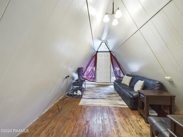 additional living space featuring hardwood / wood-style flooring, wood walls, vaulted ceiling, and a chandelier