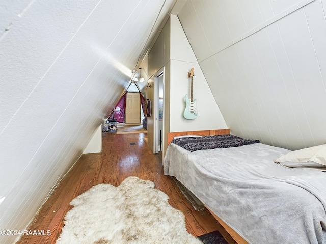 bedroom with wood walls, dark hardwood / wood-style floors, and vaulted ceiling