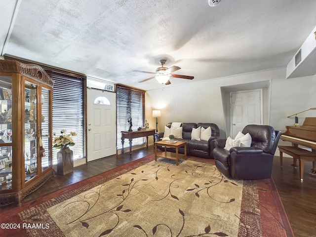 living room with ceiling fan, ornamental molding, a textured ceiling, and dark hardwood / wood-style flooring