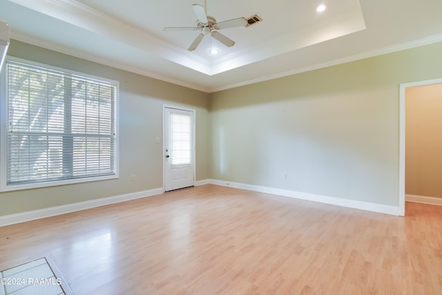 unfurnished room with ornamental molding, light wood-type flooring, a tray ceiling, and ceiling fan