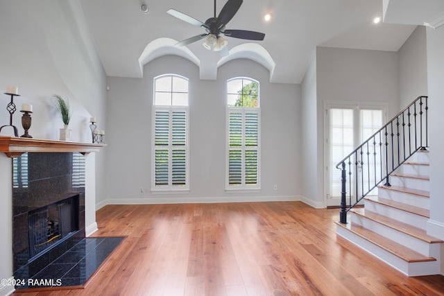 living room with plenty of natural light, a tile fireplace, ceiling fan, and light hardwood / wood-style floors