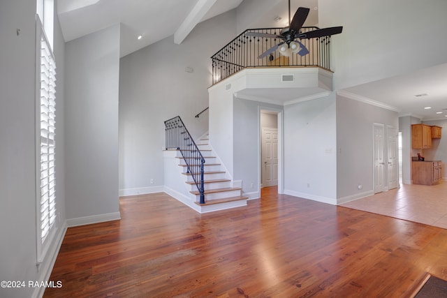 unfurnished living room with ceiling fan, ornamental molding, high vaulted ceiling, and hardwood / wood-style flooring