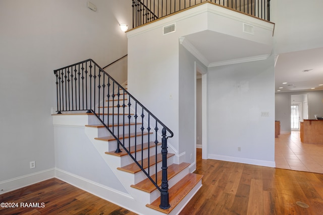 stairway with ornamental molding and wood-type flooring