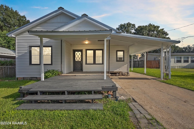 view of front facade featuring an attached carport, concrete driveway, a front lawn, and fence