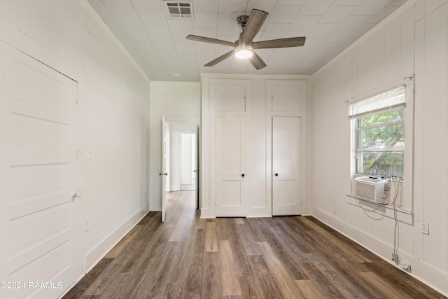 unfurnished bedroom with cooling unit, visible vents, baseboards, and dark wood-style floors