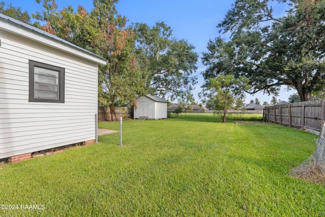 view of yard with an outbuilding, a fenced backyard, and a shed