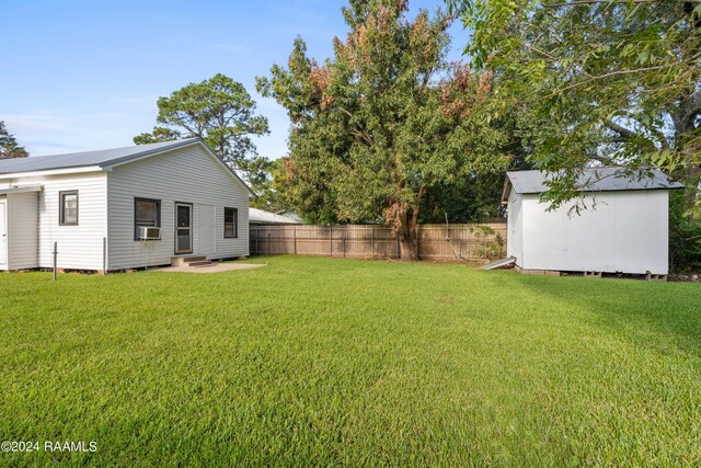 view of yard featuring an outbuilding, cooling unit, fence, entry steps, and a storage unit