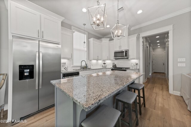 kitchen featuring sink, white cabinetry, a center island, hanging light fixtures, and appliances with stainless steel finishes